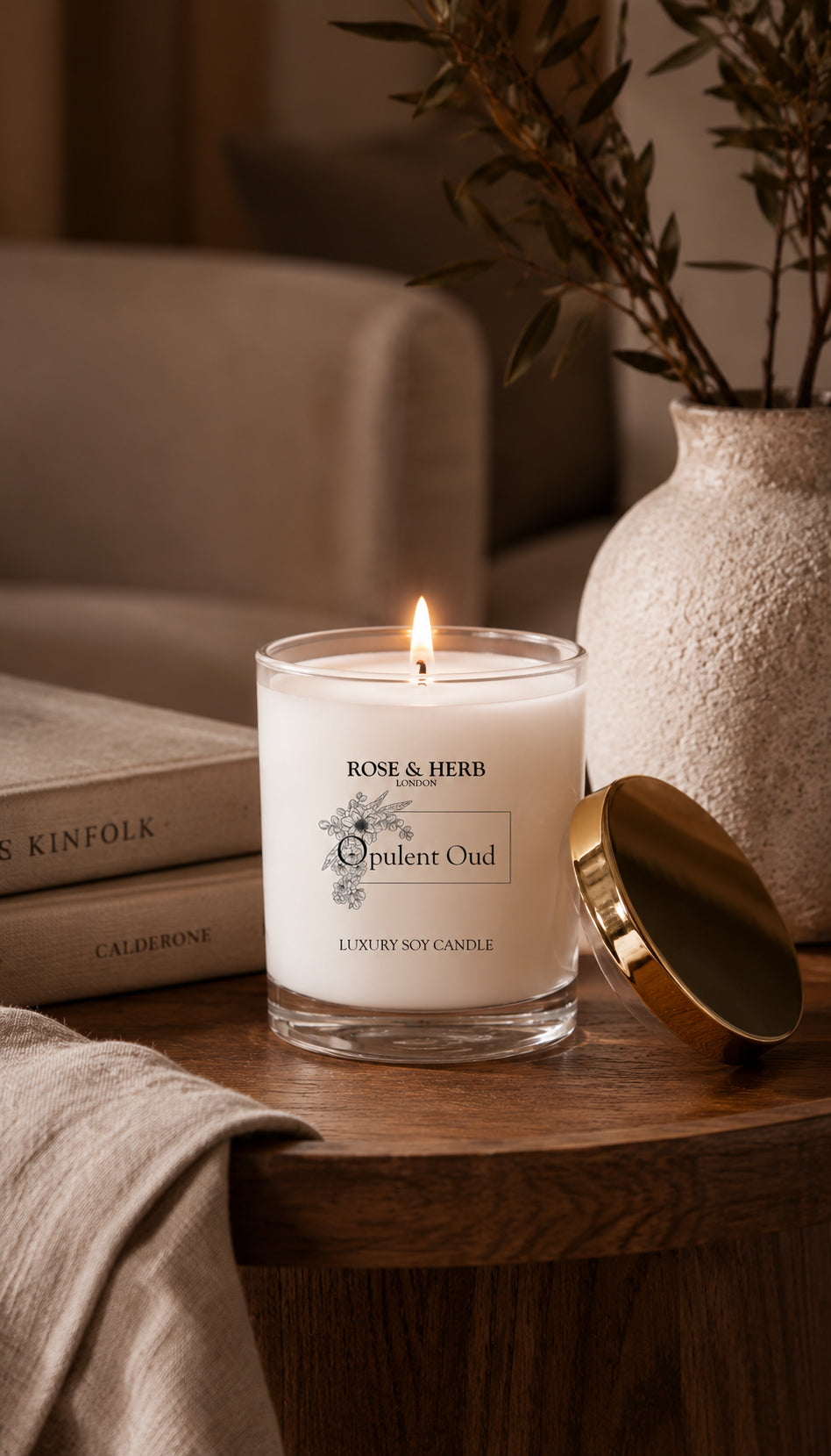Lit Opulent Oud luxury soy candle by ROSE & HERB styled on a wooden table in a warm, relaxed interior